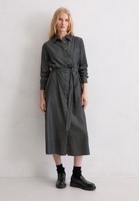 Szara sukienka na guziki z długimi rękawami i paskiem do wiązania. Wykonana z teksturowanej tkaniny, z kieszenią na piersi i długością midi. Dobierz do niej czarne buty.