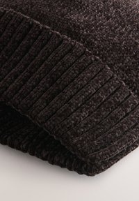 Coperta morbida di colore marrone scuro con trama in peluche e bordo a coste, che mostra una tessitura accogliente e una sottile lucentezza.