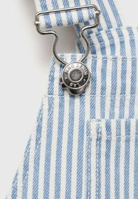 Prugasta modro-bela delovna obleka ima kovinski sponko in gumb z embosiranim napisom "MNG Denim" na teksturiranem denim blagu.