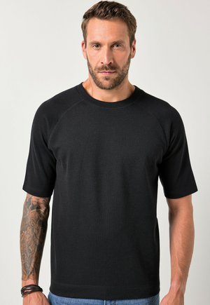 Schwarzes, kurzärmliges T-Shirt mit Rundhalsausschnitt aus glattem Stoff. Verfügt über Raglanärmel und eine subtile Textur. Trägt es mit blauen Jeans.