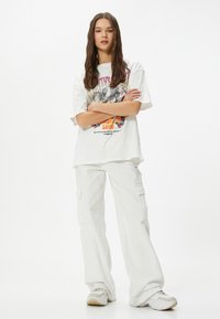 Hvid oversized t-shirt med grafisk print, parret med hvide cargo bukser. Sættet har en afslappet pasform og et uformelt design.