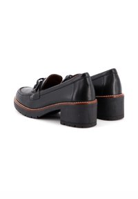 Zapatos de tacón de cuero negro con punta redonda, superficie texturizada y costuras en contraste de color marrón claro a lo largo de la suela y el tacón.