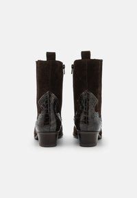 Pair of mid-calf dark brown suede boots with black textured leather heel panels and low stacked wooden heels, viewed from the back.