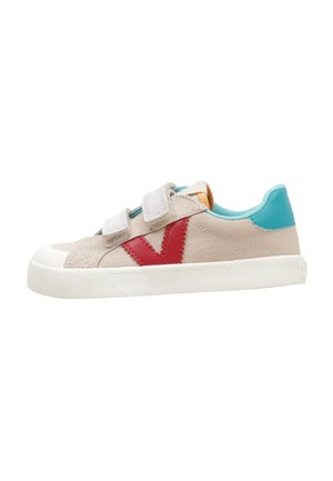 Zapatilla beige con dos tiras de velcro, logo lateral rojo, talón turquesa y suela de goma blanca.