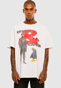 Hvid kortærmet t-shirt med et grafisk print af to figurer, med rød og sort tekst, der læser "ERIC B. & RANNN." Lavet af bomuldsstof med en afslappet pasform.
