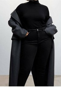 Top negro de cuello alto con una silueta ajustada combinado con jeans negros de cintura alta, cubierto por un abrigo gris de lana de gran tamaño.