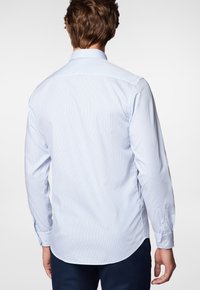 Jasnoniebieska i biała koszula z długim rękawem, z kołnierzykiem zapinanym na guziki, z tkaniny o fakturze i zaokrąglonym dolnym brzegiem.