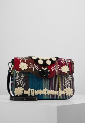 Kolorowa torebka w kratę z haftowanymi białymi kwiatowymi wzorami, czarnym zatrzaskiem i odpinanym czarnym paskiem, spoczywająca na białej powierzchni na tle szarego tła.