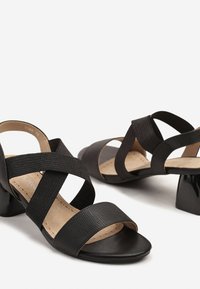 Sandales à talons noirs avec des bandes élastiques croisées, une finition texturée et une zone des orteils en cuir lisse, dotées d'un talon bloc.