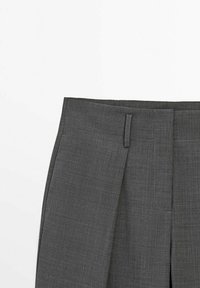 Donkergrijze op maat gemaakte broek met riemlussen en voorkruisingen, weergegeven op een witte achtergrond.
