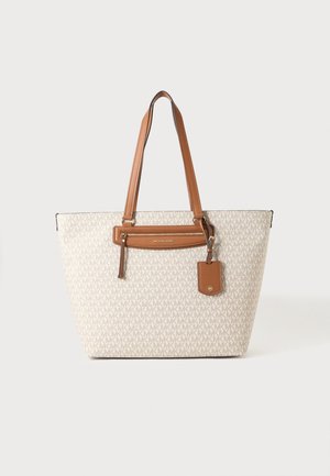 Borsa tote beige con manici in pelle marrone chiaro, tasca frontale con zip e motivo logo MK ripetuto sul corpo in tessuto, su sfondo semplice.