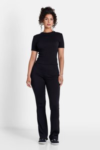 Sort tekstureret to-delt sæt bestående af en kortærmet top og tætsiddende bukser, parret med mørke sneakers. Simpel, tætsiddende silhuet.