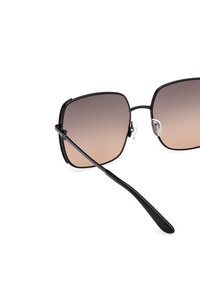 Czarne prostokątne okulary przeciwsłoneczne z gradientowymi brązowymi soczewkami. Posiadają wąskie, proste zauszniki oraz przezroczyste poduszki na nos dla wygody.