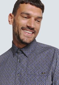 Korteblauwe shirt met korte mouwen met een geometrisch patroon in groen en wit. Heeft een button-down kraag en een detail van een borstzak.