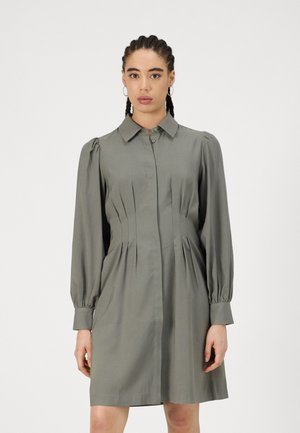 Langärmliges, kragenloses Kleid in Olivgrün, mit Falten und Knopfverschluss, aus glattem Material und mit taillierter Passform.