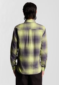 Langärmliges kariertes Hemd in Grün und Lila, mit einem Button-Down-Kragen, Brustfalten und Knöpfen an den Manschetten. Strukturierter gewebter Stoff.