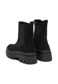 Botines de ante negro con suela de goma gruesa, que presentan paneles elásticos en los costados y una cremallera trasera para poner y quitar fácilmente.