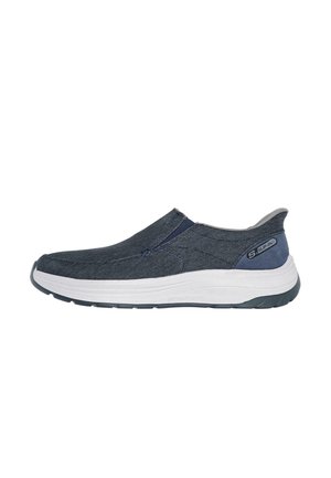 Zapatilla oscura de lona azul con parte superior de tejido texturizado, media suela blanca y acentos en azul marino contrastantes. Presenta un diseño flexible y acolchado.