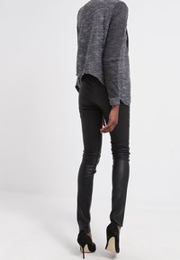 Svarta leggings i konstläder med en stram passform, tillsammans med en texturerad, kortärmad topp med hög-låg fålldesign.