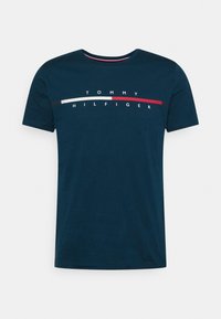 Tmavě modré tričko s krátkým rukávem s textem "Tommy Hilfiger" a horizontálním pruhem v červené, bílé a tmavě modré barvě přes hruď.
