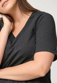 Czarny bawełniany t-shirt z dekoltem w serek, krótkimi rękawami i gładką teksturą. Charakteryzuje się luźnym krojem i subtelnymi detalami w szwach.