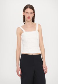 White cropped top with adjustable straps, textured fabric featuring horizontal eyelet patterns, and a square neckline.