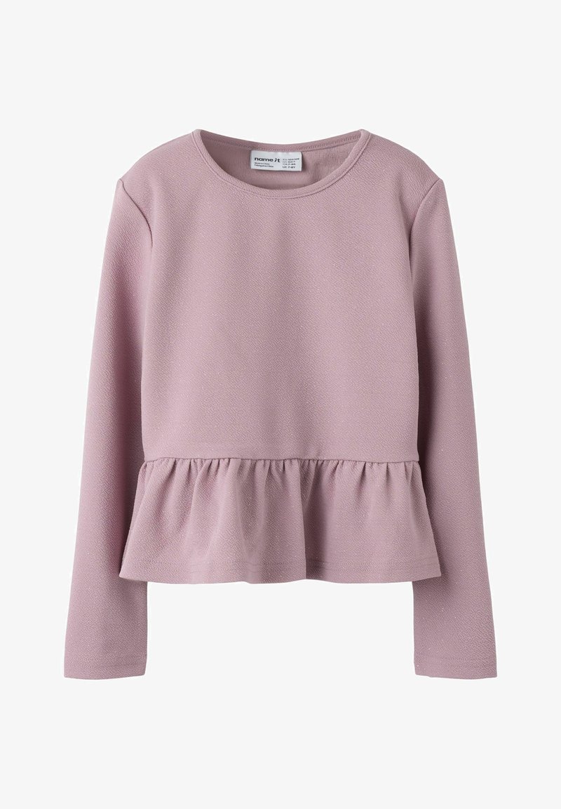 Vaaleanpunainen pitkähihaine paita, joka on valmistettu teksturoidusta kankaasta ja jossa on peplum-helma. Kaula-aukko on pyöreä, eikä siinä ole näkyviä koristeita.