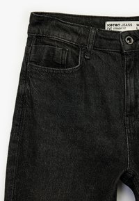 Vaqueros rectos negros hechos de mezclilla, con un diseño clásico de cinco bolsillos. Textura sutil y un pequeño bolsillo para reloj en la parte frontal.