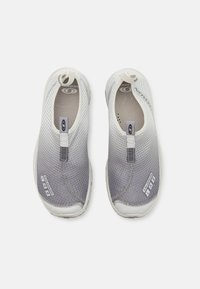Szürke és fehér slip-on cipők, hálós felső résszel, lekerekített orral és texturált dizájnnal. Húzófüllel és logó díszítésekkel az oldalán.