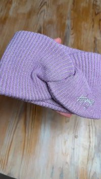 Hele lilla värviline õmblustega pähe kinnitatav peapael, mis on ees keeratud disainiga ja millel on külje peal tikitud logo.