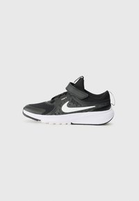 Schwarzer Sportschuh mit Mesh-Obermaterial, verstellbarem Riemen, weißem Swoosh-Logo und Gummisohle mit strukturiertem Grip-Muster.