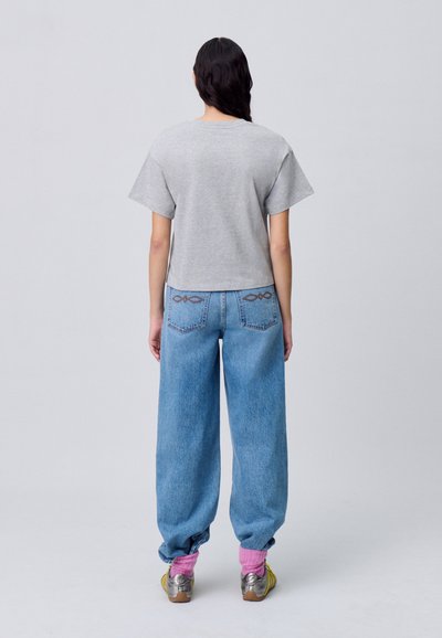 T-shirt grigio a maniche corte abbinato a jeans blu larghi. Accentuato da calzature rosa e argento, con tasche posteriori dettagliate.