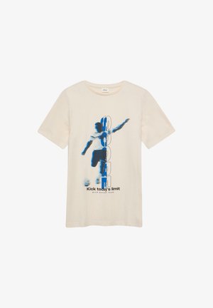 T-shirt beige à manches courtes avec un graphisme d'un joueur de football donnant un coup de pied dans un ballon, texte vertical "SOCCER" et slogan "Repousse les limites d'aujourd'hui".