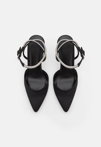 Svarta spetsiga klackar med satinfinish, som har ett dekorativt metallband och en mjuk, minimalistisk design.