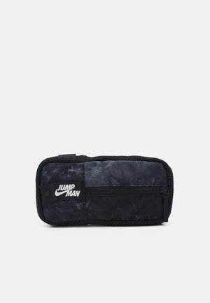 Estuche de lápices de tela negra con una superficie texturizada, que cuenta con un bolsillo con cremallera y un logo blanco de "JUMP MAN". Forma rectangular con bordes redondeados.