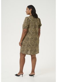 Kortskaftad klänning i leopardmönster i tan och svart, har puffärmar och avslappnad passform, med en lätt rundad nederkant baktill.