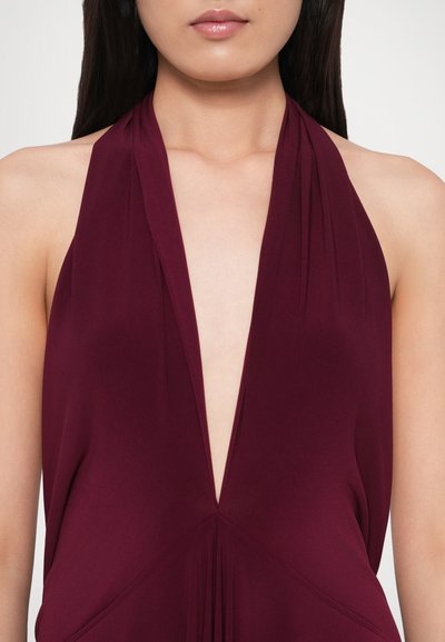 Rochie grena cu gât halter, decolteu adânc în V, țesătură drapată, pliuri în talie și textură fină, evidențiind o siluetă elegantă.