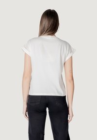 T-shirt bianco a maniche corte con risvolti, realizzato in tessuto morbido. La vista posteriore mostra una vestibilità comoda e un orlo curvo.