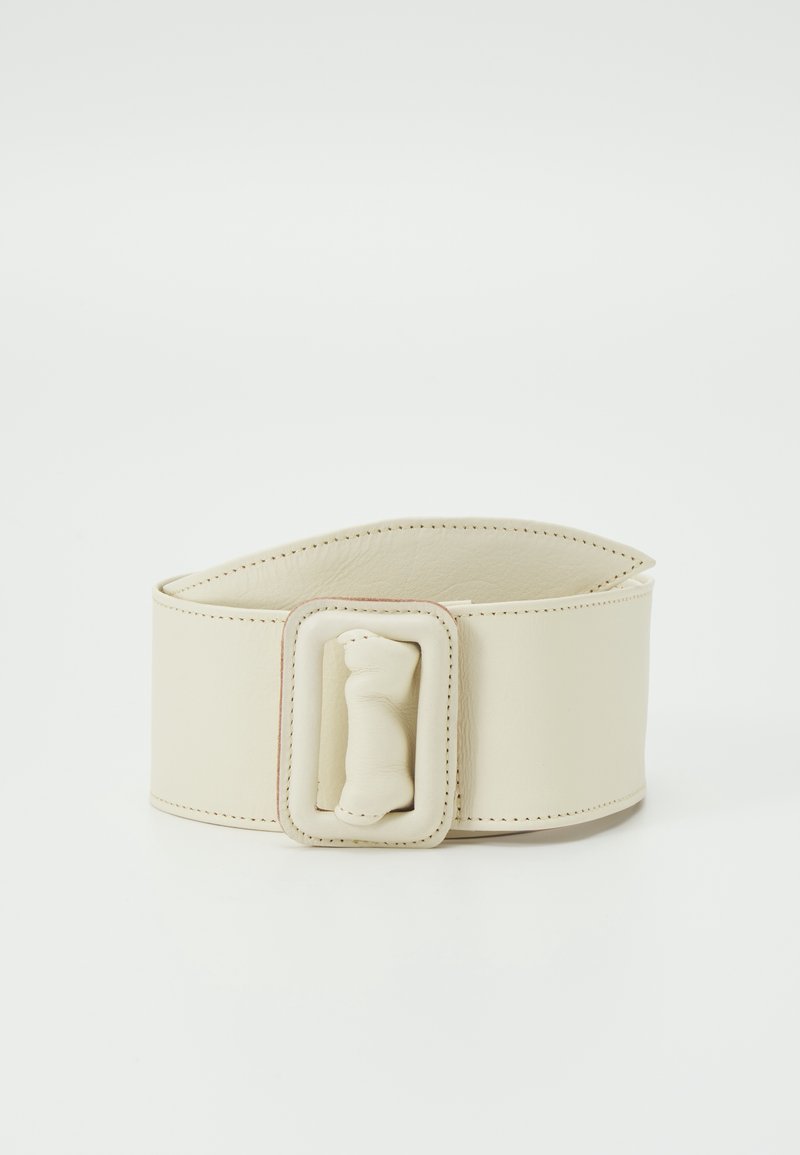 Beige bredt læderbælte med et tilpasset rektangulært polstret spænde og synlige syninger, vist på en hvid baggrund.