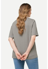 Camiseta de manga corta, gris, con un corte relajado, que presenta una textura moteada. Muestra un diseño simple sin hardware o acentos visibles.