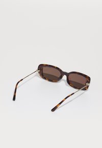 Brune skjoldbrille med rektangulære linser. Har tynne metallarmer og en glanset overflate med en jevn tekstur.