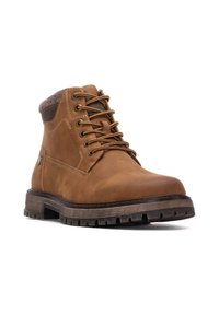 Botas de tobillo de cuero marrón con un cuello de ante texturizado, punta redonda, ojales de metal y suela de goma resistente con tacos profundos.