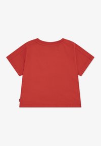 Camiseta roja de manga corta hecha de algodón. Presenta un cuello redondo, un ajuste relajado y costuras mínimas en la parte posterior.