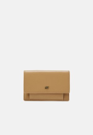 Cartera de cuero marrón claro con una textura suave, que presenta un cierre de solapa en la parte delantera y un pequeño logotipo en tono dorado en el centro. Diseño compacto y rectangular.