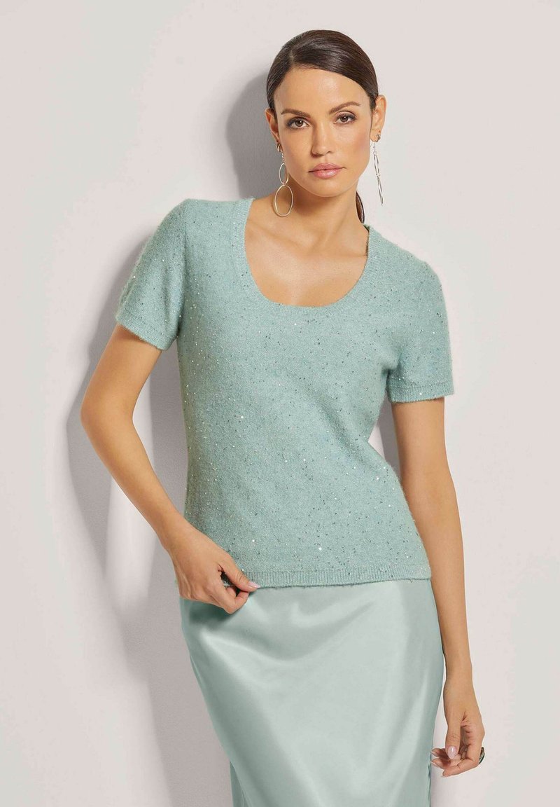 Mintgroene trui met korte mouwen en een ronde hals, met een gestructureerde brei en verspreide zilveren accenten. Zacht, lichtgewicht materiaal.