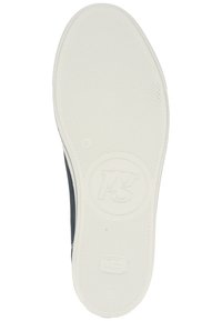 Shoe sole in white rubber with a textured grip pattern, featuring a circular logo and design elements in dark color at the edges.