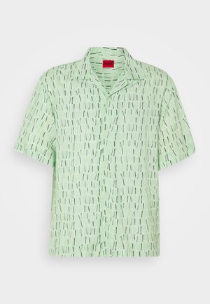 Koszula z krótkim rękawem w jasnozielonym materiale, z graficznym wzorem pionowych czarnych i białych linii. Posiada kołnierzyk i zapinanie na guziki.