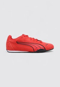 Chaussures de sport rouges avec une finition en daim, présentant des accents noirs, un design à lacets et un profil bas. Panneaux latéraux texturés et semelle lisse.