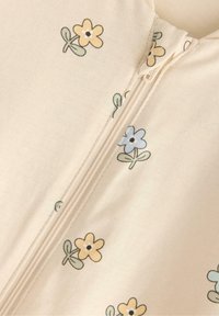 Cremefarvet lynlåsbeklædning med spredte blomsterdesigns i gul, blå og grøn. Stof er blødt med en glat tekstur og en afslappet pasform.