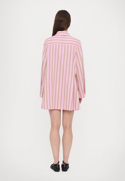 Long-sleeve shirt dress in pink with gold vertical stripes, featuring a collared neck and relaxed fit, shown from the back. Black shoes visible.